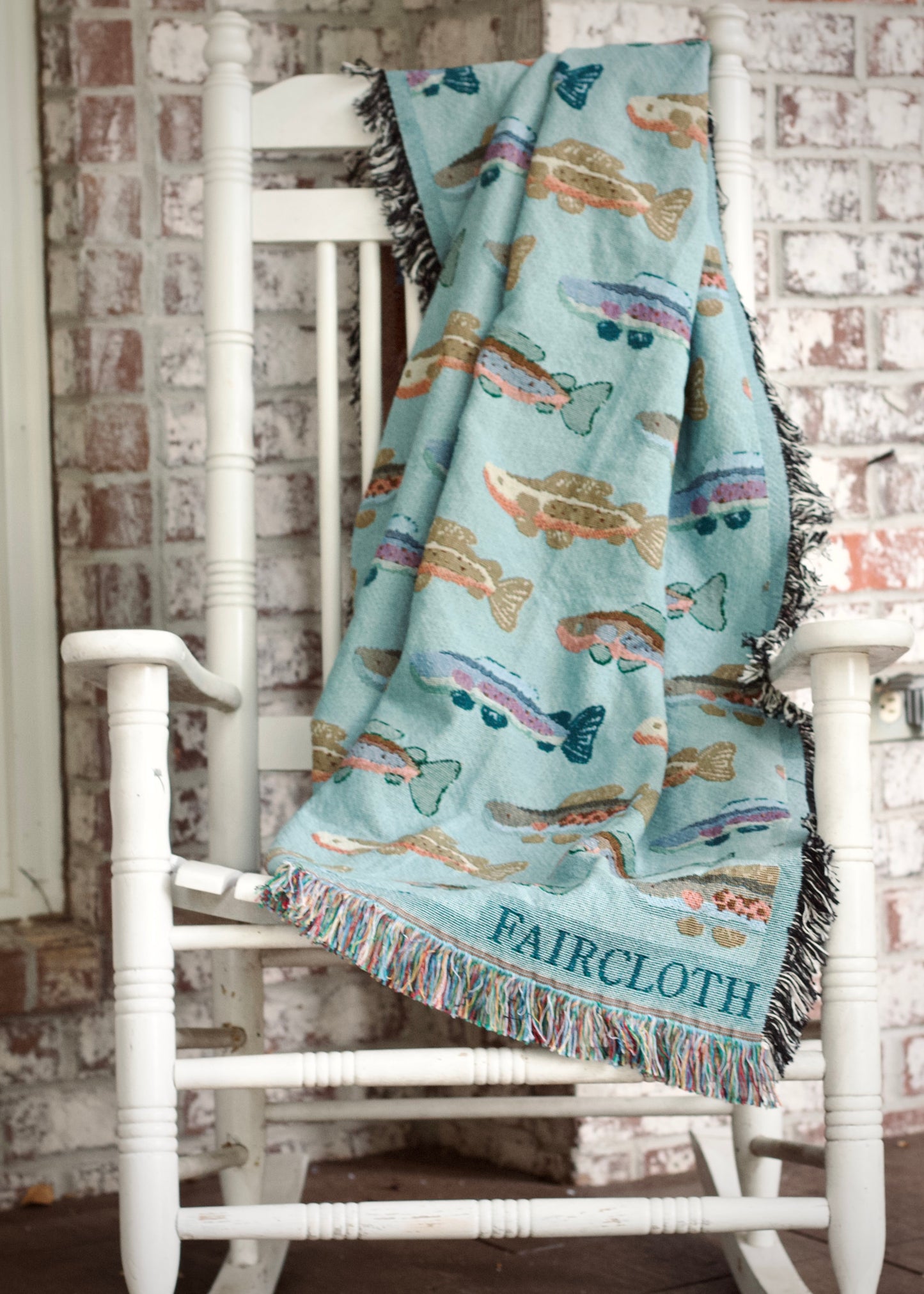 blue faircloth blanket with tiled colorful fish across it