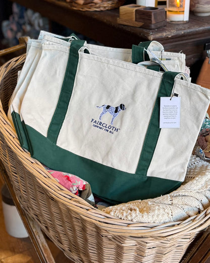 Canvas tote bags with green straps in a basket, featuring Faircloth branding.